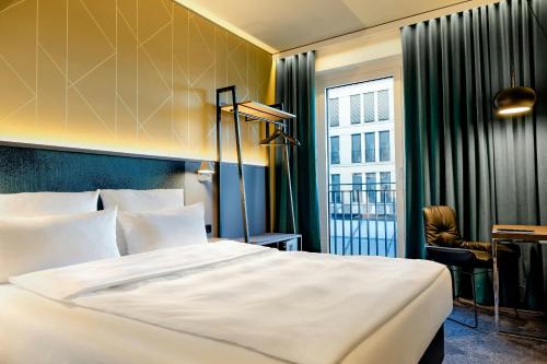 a hotel room with a bed and a desk and a window at Motel One Berlin-Potsdamer Platz in Berlin