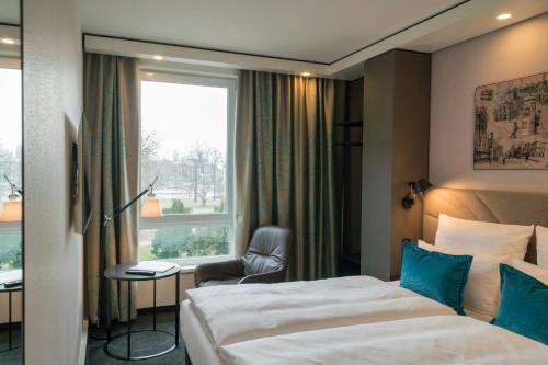 a hotel room with a bed and a chair and a window at Motel One Dresden-Palaisplatz in Dresden