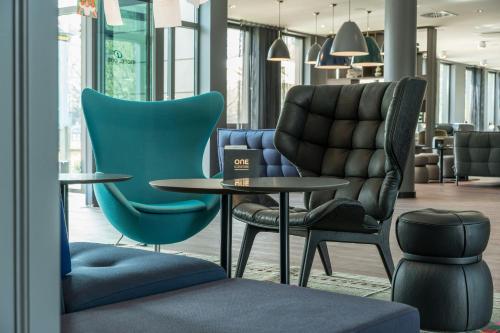 a waiting area with chairs and tables in a lobby at Motel One Dresden-Palaisplatz in Dresden