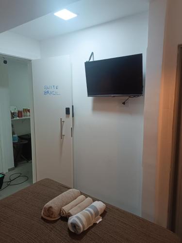 a bed with two towels and a flat screen tv at Lapa Bed & Breakfast in Rio de Janeiro