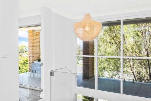 a glass staircase in a house with a large window at Mollymook Delight - with easy ocean & golf access in Mollymook