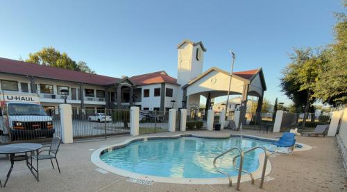 a pool with chairs and a table in front of a building at Super 8 by Wyndham Houston/Brookhollow NW in Houston