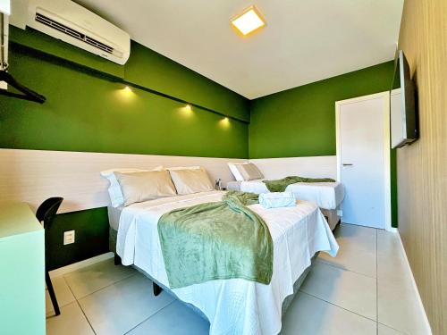 a bedroom with two beds and a green wall at Vacanze - Time in Maceió