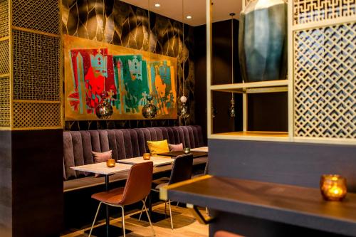 a restaurant with two tables and chairs and a painting at Motel One Aachen in Aachen