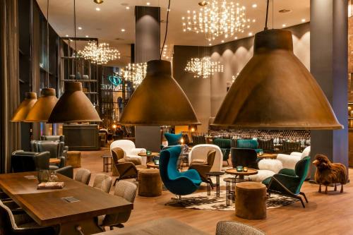 a restaurant with chairs and tables and pendant lights at Motel One Glasgow in Glasgow