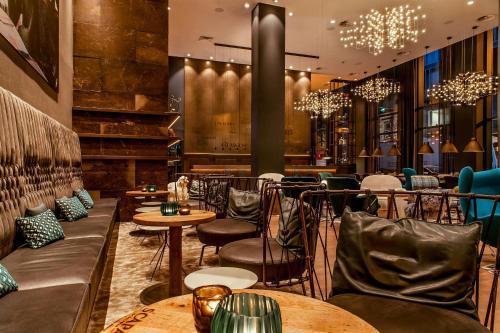 a restaurant with tables and chairs and chandeliers at Motel One Glasgow in Glasgow