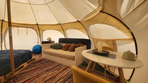 a living room with a tent with a couch and a table at Olas de Chile Ecocamp in Pichilemu