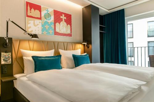 two beds in a hotel room with blue pillows at Motel One Aachen in Aachen
