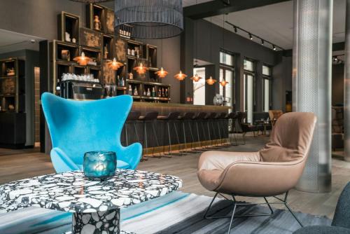 a restaurant with blue chairs and a table at Motel One Lübeck in Lübeck
