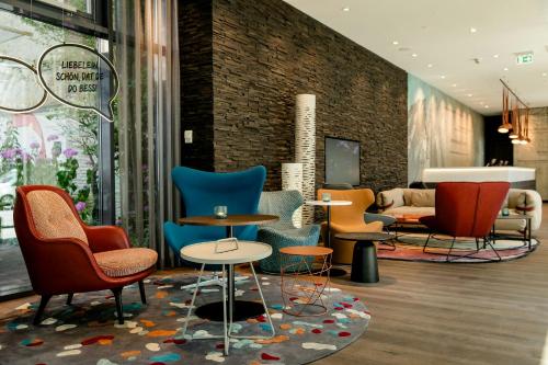 a lobby with chairs and tables in a building at Motel One Köln-Mediapark in Cologne