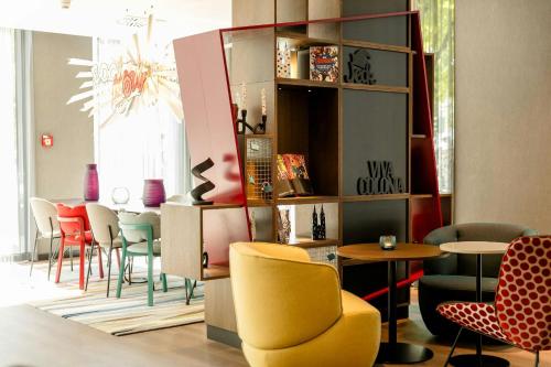 a room with chairs and tables and a room with a chandelier at Motel One Köln-Mediapark in Cologne