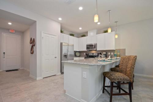 a kitchen with white cabinets and a bar with chairs at Four Bedrooms Townhouse 5102 in Kissimmee
