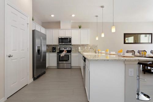 a kitchen with white cabinets and stainless steel appliances at Four Bedrooms TownHome 5130 in Kissimmee