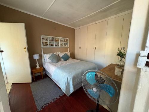 a bedroom with a bed with a fan and a table at Wiltshire Cottage in Port Alfred