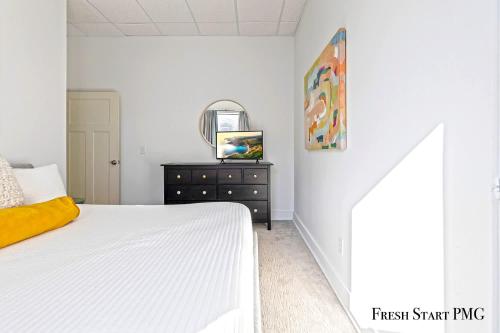 a white bedroom with a bed and a dresser at City View Loft in Saint Joseph