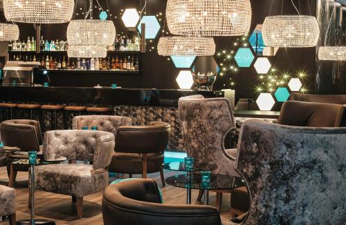 a bar with chairs and tables and chandeliers at Motel One London-Tower Hill in London