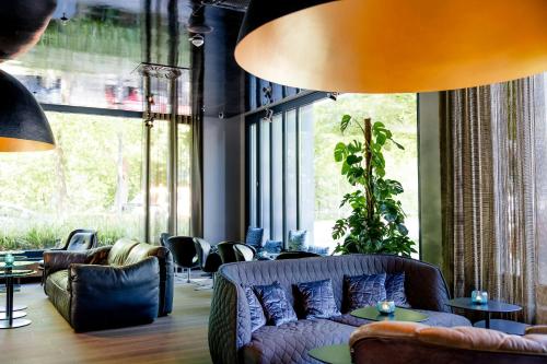 a living room with a couch and chairs and windows at Motel One München-Deutsches Museum in Munich