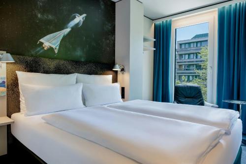 a bedroom with a white bed and a window at Motel One München-Deutsches Museum in Munich