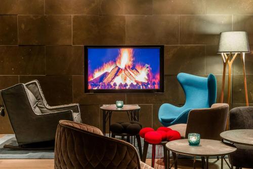 a lobby with chairs and a tv on a wall at Motel One Freiburg in Freiburg im Breisgau