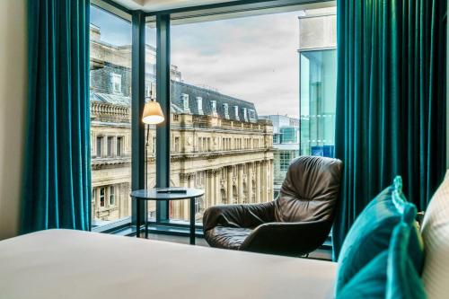 a room with a chair and a large window at Motel One Manchester-Royal Exchange in Manchester