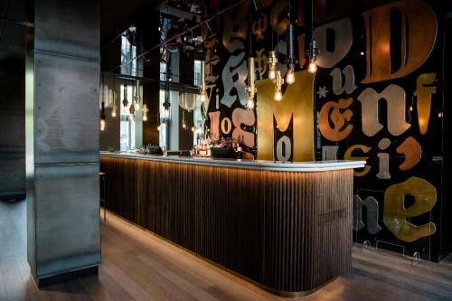 a bar in a restaurant with a black wall with chandeliers at Motel One Hannover-Oper in Hannover