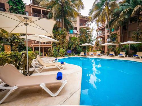 a swimming pool with lounge chairs and umbrellas at Tukan Hotel Playa del Carmen in Playa del Carmen