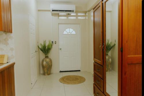 a hallway with a white door and a vase at Bali-Inspired Studio Mins from Airport in Arima