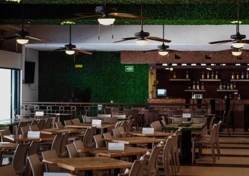 a restaurant with wooden tables and chairs and a green wall at Tukan Hotel Playa del Carmen in Playa del Carmen