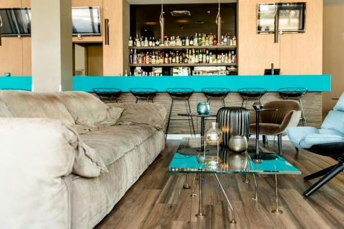 a living room with a couch and a bar at Motel One München-Garching in Garching bei München