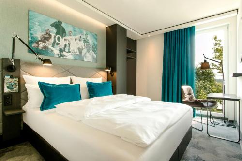 a bedroom with a large white bed with blue pillows at Motel One München-Garching in Garching bei München