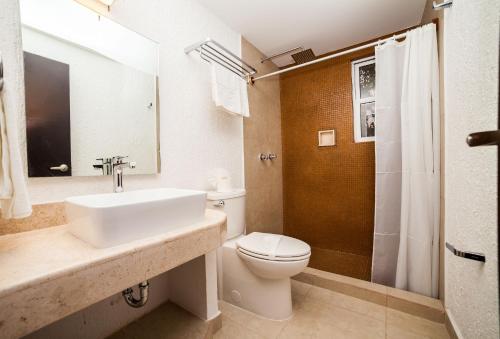 a bathroom with a sink and a toilet and a shower at Tukan Hotel Playa del Carmen in Playa del Carmen