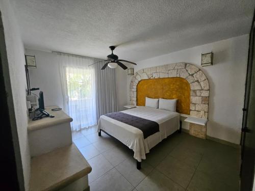 a bedroom with a large bed and a stone wall at Tukan Hotel Playa del Carmen in Playa del Carmen