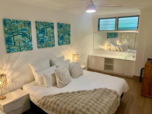 a bedroom with a large white bed and a bathroom at Hamilton Island Poinciana 008 Ground Floor 2bedrooms Free Buggy in Hamilton Island