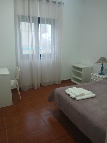 a bedroom with a bed and a chair and a window at Centro Da Vila in Lourinhã