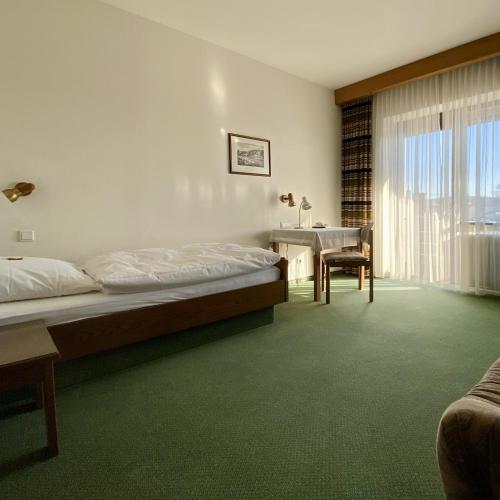 una camera da letto con un letto, una scrivania e un tavolo di Hotel Krieger Regensburg a Pettendorf