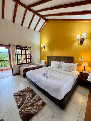 a bedroom with a large bed and a yellow wall at Hotel Bosque de la Villa in Villa de Leyva