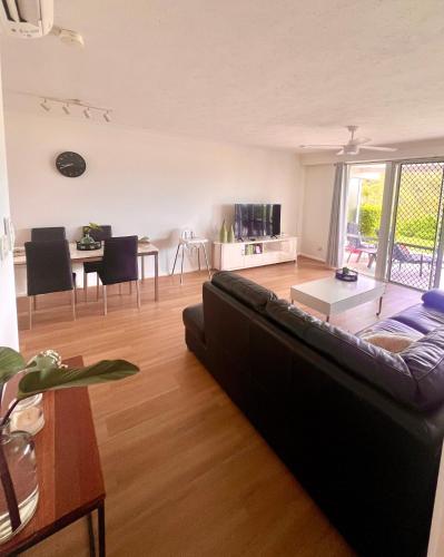 a living room with a black couch and a table at Hamilton Island Poinciana 008 Ground Floor 2bedrooms Free Buggy in Hamilton Island