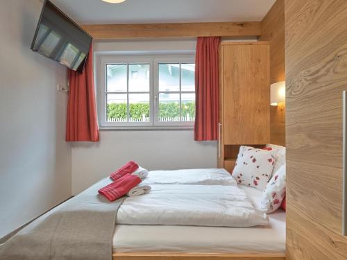 a bedroom with a bed with red curtains and a window at Bergbiberhaus L in Piesendorf