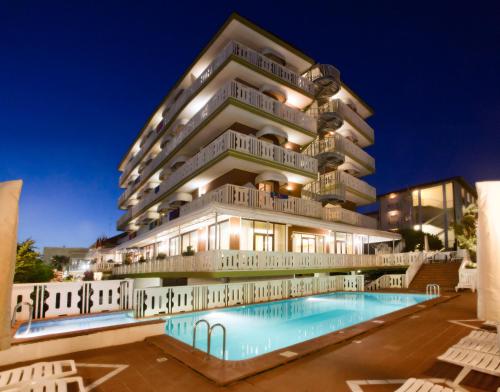 um hotel com piscina em frente a um edifício em Hotel Savoy em Caorle