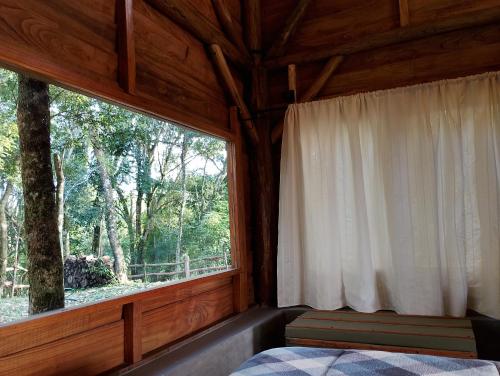 a bedroom with a large window in a cabin at Morada da Mata in Candelária
