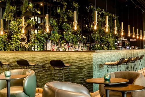 a bar with tables and chairs and plants at Motel One München-East Side in Munich
