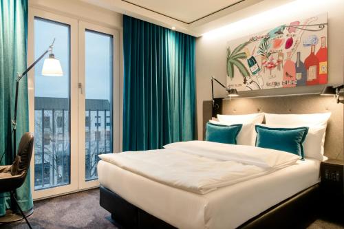 a bedroom with a bed and a large window at Motel One München-Haidhausen in Munich