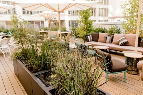 an outdoor patio with tables and chairs and plants at Motel One München-Haidhausen in Munich