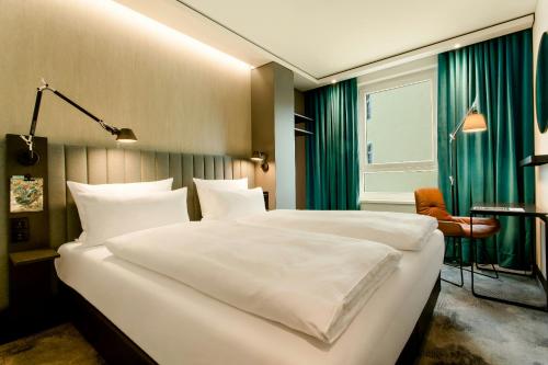 a bedroom with two large white beds and a chair at Motel One München-East Side in Munich