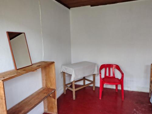 a red chair sitting next to a table and a mirror at Hostal Mama Julia - Sede Urbana - Casa Coibrí in Sibundoy