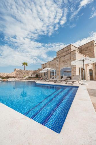 an image of a swimming pool in front of a house at L-Eremita Boutique Hotel in Qala