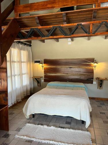 a bedroom with a large bed with a wooden headboard at Cabañas El Alemán in Cerrillos