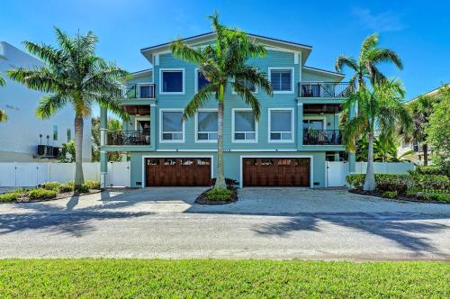 a blue house with palm trees in front of it at Anna Maria Island Beach Palace in Bradenton Beach