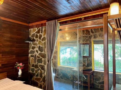 a bedroom with a shower and a stone wall at Trang An Mountain Ecologe in Xuân Sơn
