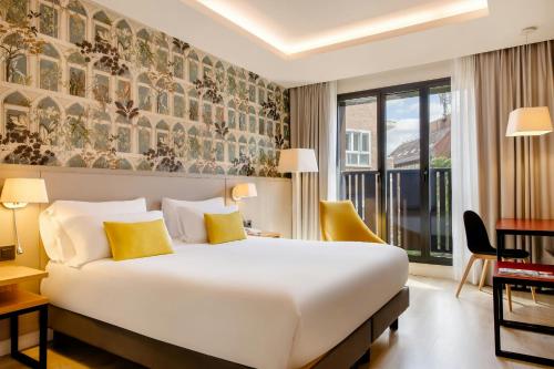 a hotel room with a large bed with yellow pillows at Motel One Madrid-Plaza de España in Madrid